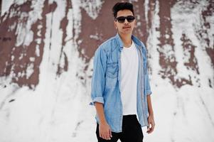 jeune homme indien décontracté en chemise de jeans bleu et lunettes de soleil posées le jour de l'hiver. photo