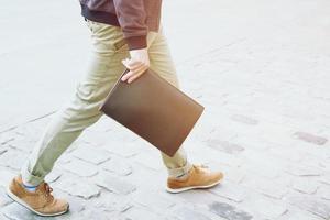 gros plan homme d'affaires en tenue décontractée. main tenant le sac de documents porte-documents rue piétonne sur la route. photo