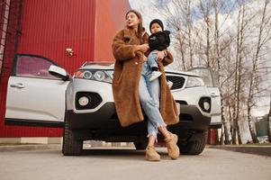 jeune mère et enfant se tiennent près de leur voiture suv. concept de conduite de sécurité. photo