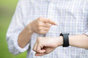 jeune homme attend avec impatience la minuterie regardant l'horloge. réunion prendre rendez-vous dans le délai imparti. montre-bracelet photo