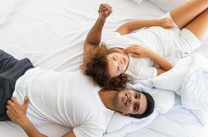 beau couple allongé, parlant, sur une couverture blanche dans la chambre. relation dans la famille. détente le matin. photo