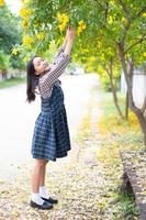 jeune fille debout sous un arbre à fleurs jaunes. photo