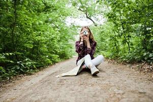 portrait d'une jolie fille blonde avec une carte assise dans la forêt et prenant des photos. photo