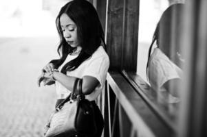 élégante femme d'affaires afro-américaine avec sac à main dans les rues de la ville et regardant des montres. photo