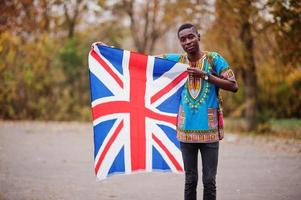 homme africain en chemise traditionnelle africaine sur le parc d'automne avec le drapeau de la grande-bretagne. photo