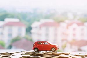 petite voiture rouge sur beaucoup d'argent pièces empilées avec maison de fond. pour le concept de financement des coûts de prêts. avec des tons de filtre effet rétro vintage, des tons chauds. photo