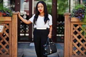 élégante femme d'affaires afro-américaine avec sac à main dans les rues de la ville. photo