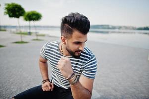 beau grand modèle d'homme à barbe arabe à chemise dépouillée posé à l'extérieur. mec arabe à la mode. photo