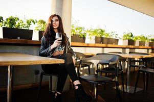 jeune femme frisée dégustant son vin dans un bar. photo