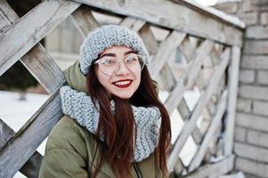 portrait de jeune fille brune en écharpe et chapeau gris, lunettes par temps froid. photo