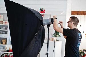 le photographe ajuste la lumière du flash sur le studio. photo