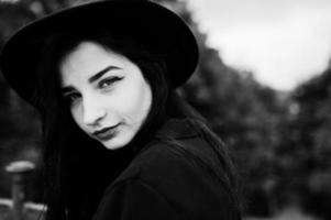 fille sensuelle tout en noir, lèvres rouges et chapeau. femme dramatique gothique. portrait en noir et blanc. photo