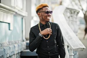 chic bel homme afro-américain en chemise noire avec chaîne en or et lunettes de soleil. photo