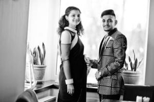 joli couple indien amoureux, porter au sari et costume élégant, posé sur le restaurant contre la fenêtre. photo