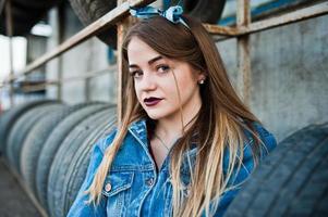 jeune fille hipster en veste jeans et foulard à la zone de montage des pneus. photo