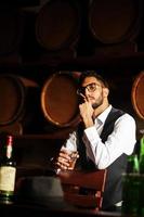 bel homme arabe bien habillé avec un verre de whisky et de cigare posé au pub. photo