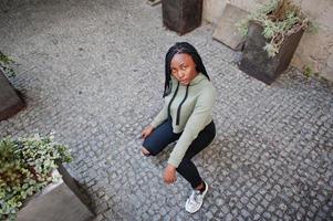 portrait de la ville d'une jeune femme positive à la peau foncée portant un sweat à capuche vert. photo