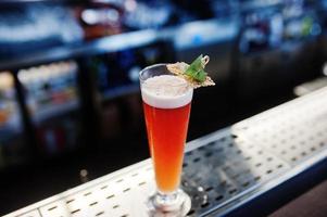 long cocktail alcoolisé en verre à table de bar. photo
