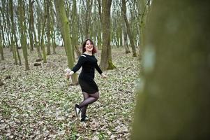 portrait de jeune fille brune en robe noire au bois de printemps. photo