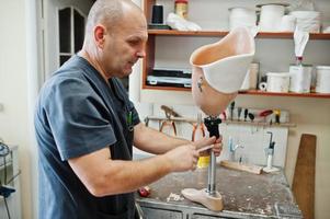 homme prothésiste fabriquant une jambe prothétique tout en travaillant en laboratoire. photo