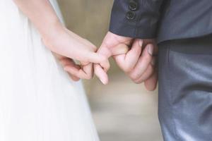 aimer les jeunes amour couple marié main dans la main et se tenir ensemble dans la scène du jour du mariage cérémonie mariage. jeune couple amoureux être main dans la main promesse pinky ou jure pinky. photo