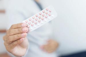 mains de femme ouvrant des pilules contraceptives à la main. manger la pilule contraceptive. la contraception réduit le concept d'accouchement et de grossesse. photo