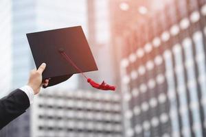 diplômés de l'université, homme d'affaires tenant des chapeaux avec succès, ton de filtre extérieur ensoleillé le matin. fond de bureau. nouveau diplômé commence à travailler le premier jour. notion d'éducation. photo