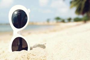 lunettes de soleil sur la plage tropicale de sable. voyage détente vacances - mer d'azur, sable blanc, concept voyage vacances paradis d'été. photo