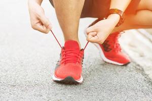 mains d'athlètes masculins attachant des lacets sur des chaussures de course avant l'entraînement. coureur se prépare pour l'entraînement. concept de mode de vie actif sportif. photo