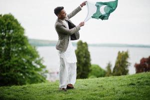 l'homme pakistanais élégant porte des lunettes et une veste tient le drapeau du pakistan. photo