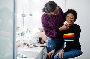 femme afro-américaine se maquillant par une maquilleuse au salon de beauté. photo