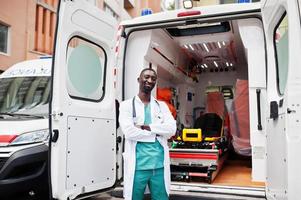 paramédic masculin africain debout devant la voiture d'ambulance. photo