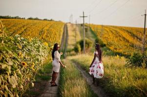 deux jolies jeunes amies noires femme portent une robe d'été posent dans un champ de tournesol. photo