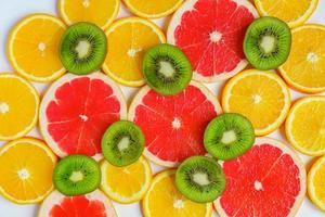 cadre avec tranche d'oranges, citrons, kiwi, motif de pamplemousse isolé sur fond blanc. mise à plat, vue de dessus photo
