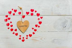 grand coeur rouge en papier découpé petits coeurs et coeur en bois avec inscription je t'aime sur fond en bois. décoration faite à la main pour la saint valentin. photo