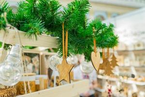 décoration intérieure de noël. jouets en bois de différentes formes étoile, coeur, sapin suspendu à une branche de sapin photo