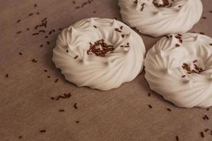 meringues à l'air blanc maison et décorations de confiserie sur papier sulfurisé. photo