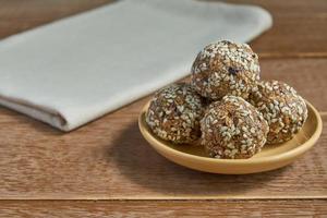 boulettes de protéines de sésame à l'avoine. bouchées énergétiques faibles en gras avec flocons d'avoine, noix de sésame et pruneaux sur fond de bois photo