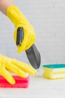 femme dans des gants en caoutchouc jaune tenant une éponge de nettoyage. nettoyer la cuisine blanche après la cuisson photo