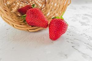 fraises biologiques fraîches dans un panier sur fond texturé gris. photo