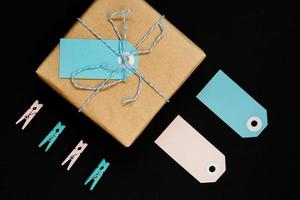 coffrets cadeaux artisanaux enveloppés dans du papier kraft avec étiquette en papier bleu et rose, corde et pinces à linge en bois pour la décoration. photo