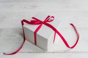 boîte-cadeau à pois beige avec noeud de ruban rouge sur fond en bois avec espace de copie. photo