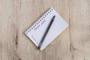 concept d'entreprise et de bureau - cahier vierge et stylo noir sur table en bois. objectifs 2019. mise à plat minimale, vue de dessus. photo