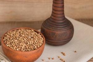sarrasin sec dans un bol d'argile brune sur une table en bois. céréales sans gluten pour une alimentation saine photo