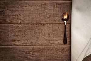 vue de dessus d'une serviette en tissu de couleur beige et d'une cuillère à thé servie sur une table en bois. photo