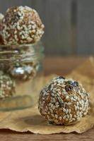 De savoureuses truffes de protéines brutes végétaliennes ou des boules d'énergie avec des pruneaux, des graines et des noix dans un bocal sur fond de bois photo