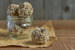 De savoureuses truffes de protéines brutes végétaliennes ou des boules d'énergie avec des pruneaux, des graines et des noix dans un bocal sur fond de bois photo