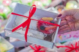 main féminine tenant une boîte avec des bonbons. pâtisserie emballée pour le cadeau photo