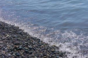 littoral de galets. bord de mer avec eau transparente et petites pierres photo