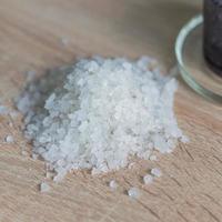 tas de sel de mer sur table en bois. ingrédient naturel pour le spa et l'exfoliation. photo